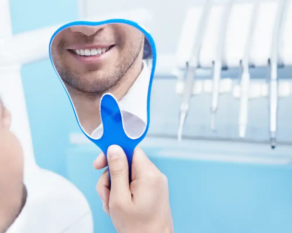 Paciente en consulta viendo el resultado del tratamiento de estética dental.