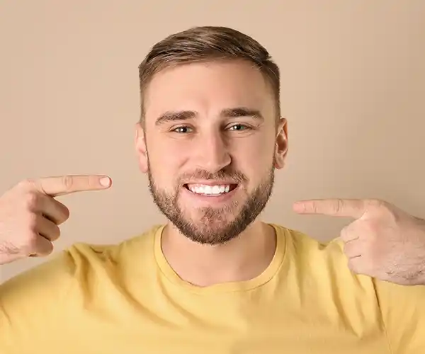 Chico señalando su sonrisa tras una reconstrucción dental.
